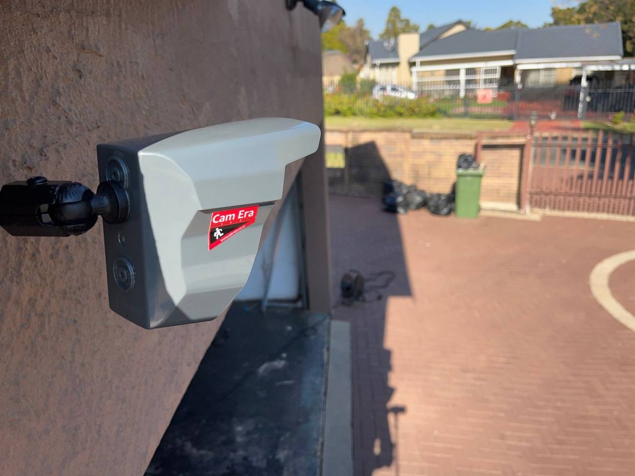 Cam Era camera on a bracket beside a paved driveway